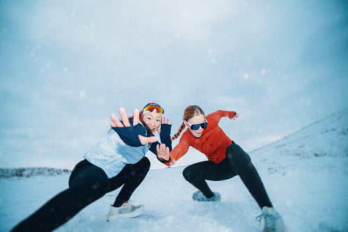 Playful women demonstrating winter fitness with snowy poses