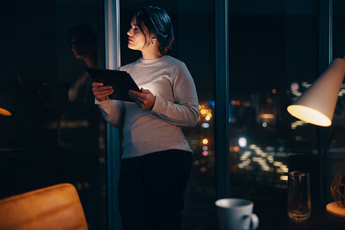 Pensive entrepreneur using digital tablet in nighttime office