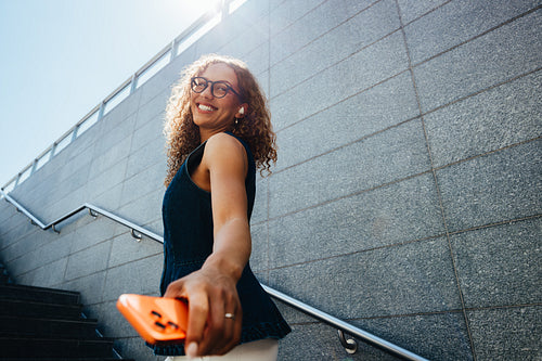 Cheerful woman enjoys city commute with smartphone on outdoor stairs
