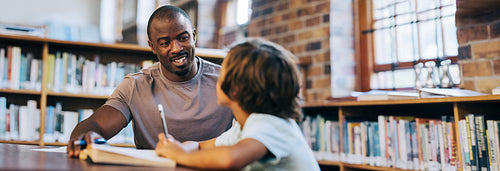 Male teacher counselling a young school boy in a library