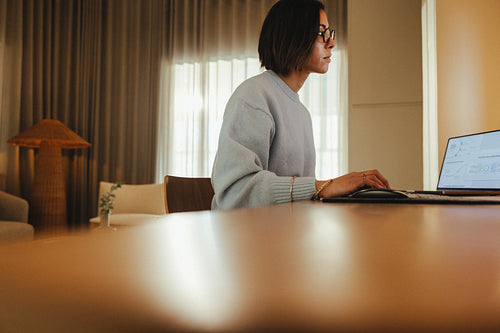 Woman concentrates on her laptop at a desk in a home office