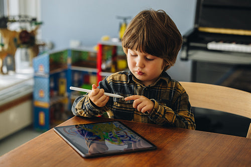 Boy using stylus to draw on digital tablet