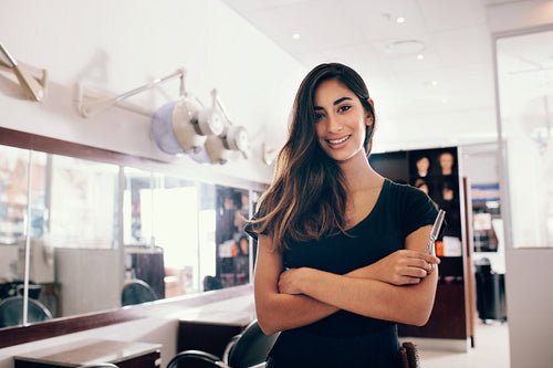 Portrait of female hairdresser standing at salon