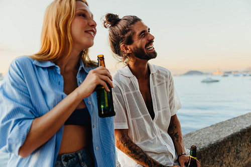Friends enjoying drinks by the waterside during sunset