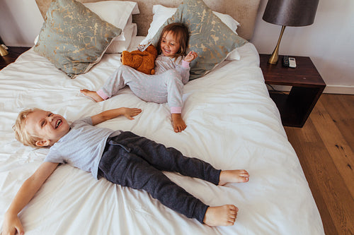 Joyful little children playing on bed