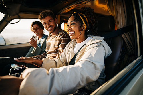 Friends on a road trip ride share laughter while driving in a sunny vehicle