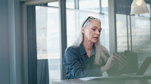 Mature businesswoman texting on her phone at office
