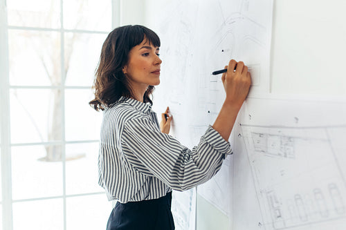 Architect drawing plans on wall charts