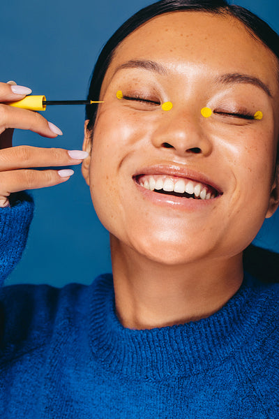 Eyeliner dots: Female applies colourful eye makeup in a studio