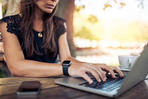 Woman working on laptop at an outdoor cafe