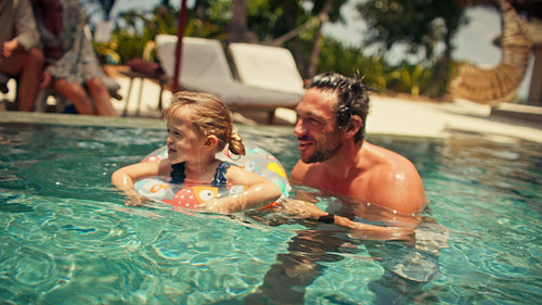 Joyful family vacation with parents and daughter swimming together in a beautiful pool