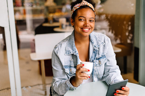 Young woman enjoying hot coffee and technology in cafe