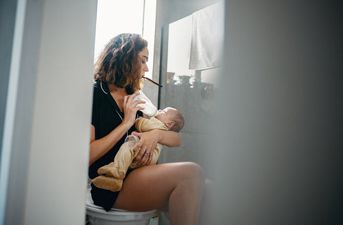 Mother brushes teeth while feeding baby