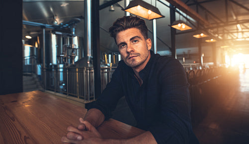 Male manufacturer sitting at table in microbrewery