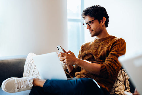 Young man reviews text messages between tasks
