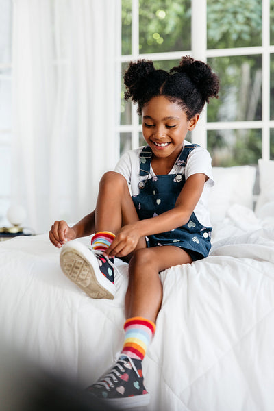 Young girl tying her shoes on the bed
