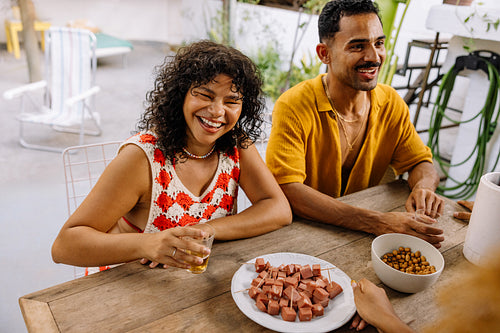 Brazilian friends laughing and eating petiscos with drinks in Rio de Janeiro
