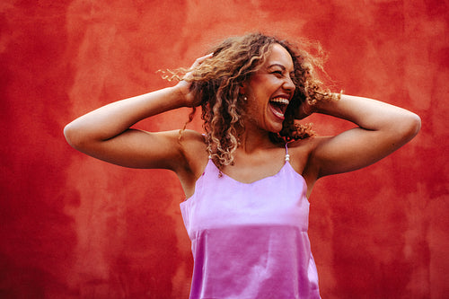 Playful woman joyfully lifts her curly hair in outdoor portrait