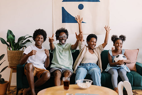 Excited Brazilian family cheers as they watch a game of football at home