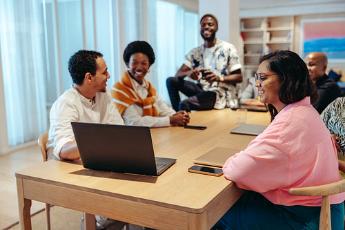 Advertising agency coworkers engaging in a lively brainstorming session around a wooden table