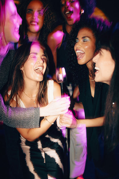 Women enjoying a vibrant party with singing and colorful lighting effects