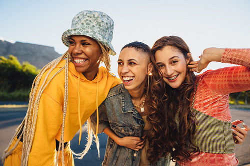 Three friends smiling while embracing each other