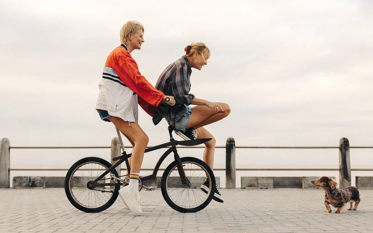 Joyful bike ride by the seaside: Two female friends having fun outdoor ...