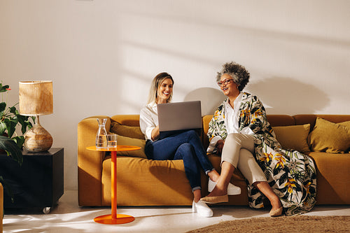 Smiling businesswomen using a laptop in an office lobby