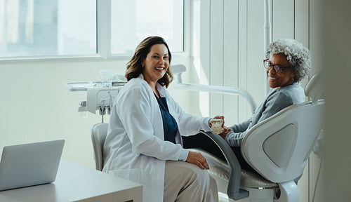 Older patient interacts with dentist in dental clinic treatment room