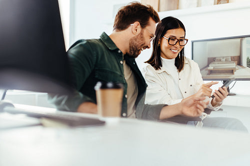 Interior designers using a mobile phone together in an office