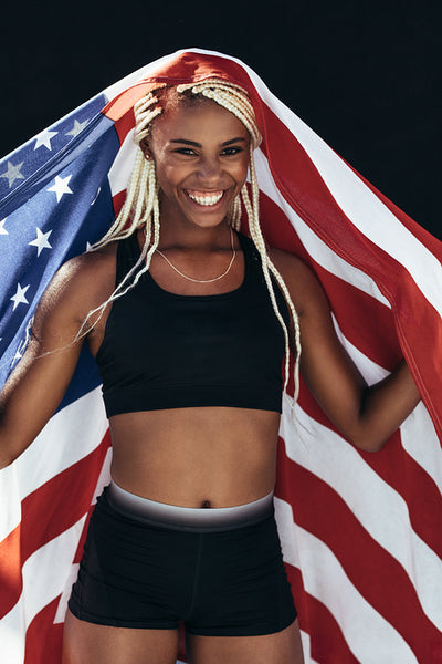 Female athlete celebrating victory holding american flag