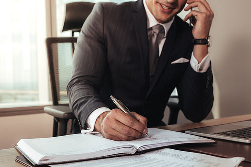 Entrepreneur writing notes and talking on phone