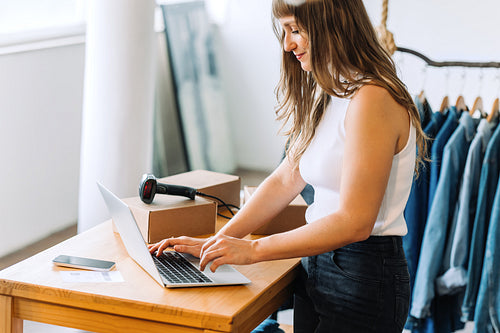 Happy online store owner using a laptop in her shop
