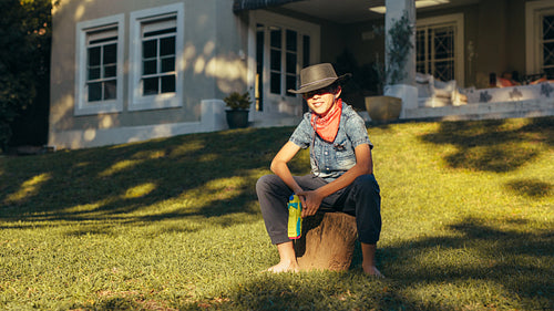 Little cowboy in backyard with water pistol