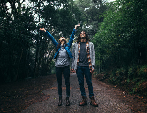 Couple having fun in rain in forest