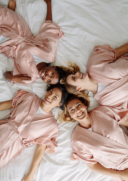 Bride with bridesmaids lying on bed and smiling
