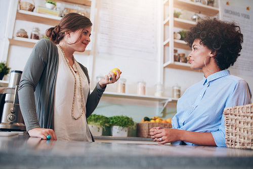 Two young female employees standing behind juice bar counter