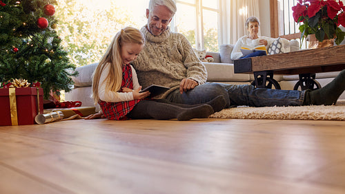 Senior man with granddaughter using digital tablet at home
