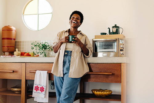 Happy Brazilian woman enjoying a hot cup of coffee in the kitchen