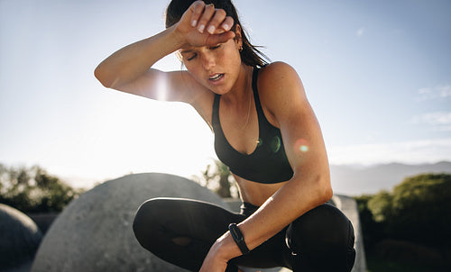Tired woman sitting and resting after workout