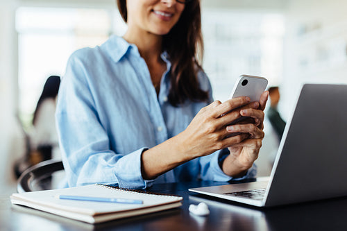 Business woman using a mobile phone at her desk