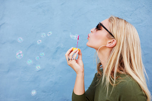 Attractive female blowing soap bubbles