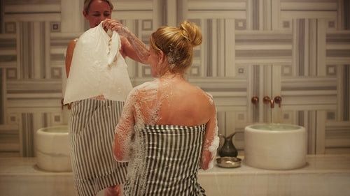 Women enjoying a traditional hammam foam bath treatment in a luxurious spa