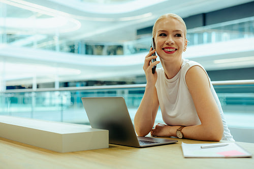 Smiling blonde salesperson using a phone in modern office