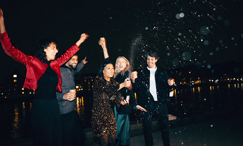 Friends celebrating New Year’s Eve with fireworks and champagne outdoors