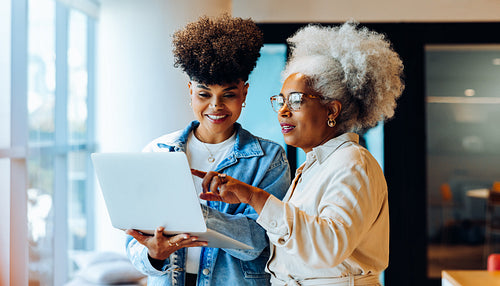 Older and younger women collaborate on tablet in office