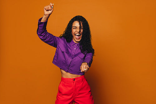Vibrant woman dancing with joy on colourful background