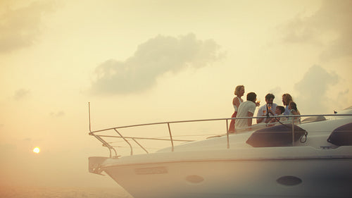 Multi generational family making a toast on a stunning yacht as the sun sets
