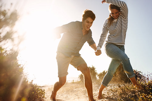 Happy man and woman running on the beach having fun