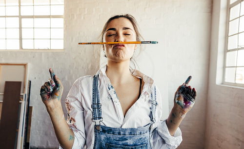 Playful female painter making a face with a paintbrush